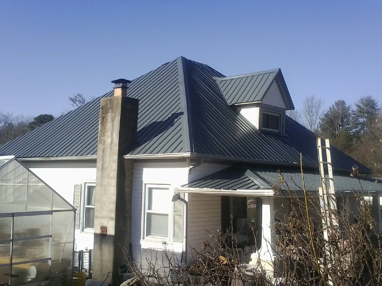 Dark blue standing seam metal roof on a white farmhouse with dormer — Slate & Tile Roof Repair by Roofing Brothers in Etta