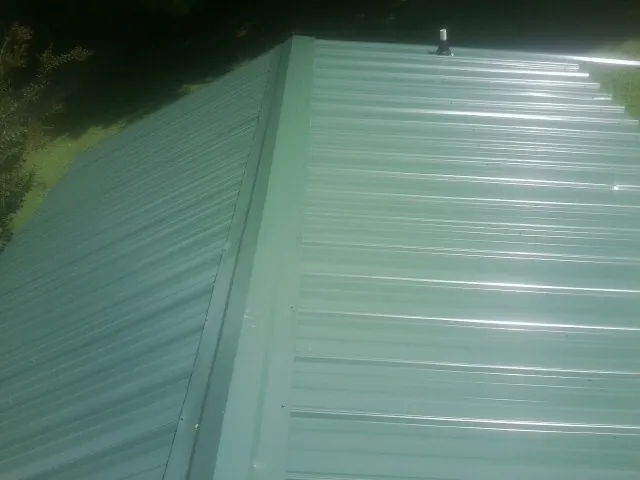 New green metal panels meeting at the ridge of a roof — Flat Roof Repair work by our crew in Etta