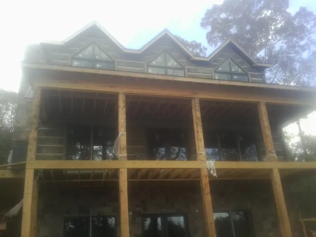 Dormers and porch framing on a large log home under construction — Roof Coating work by our crew in Etta