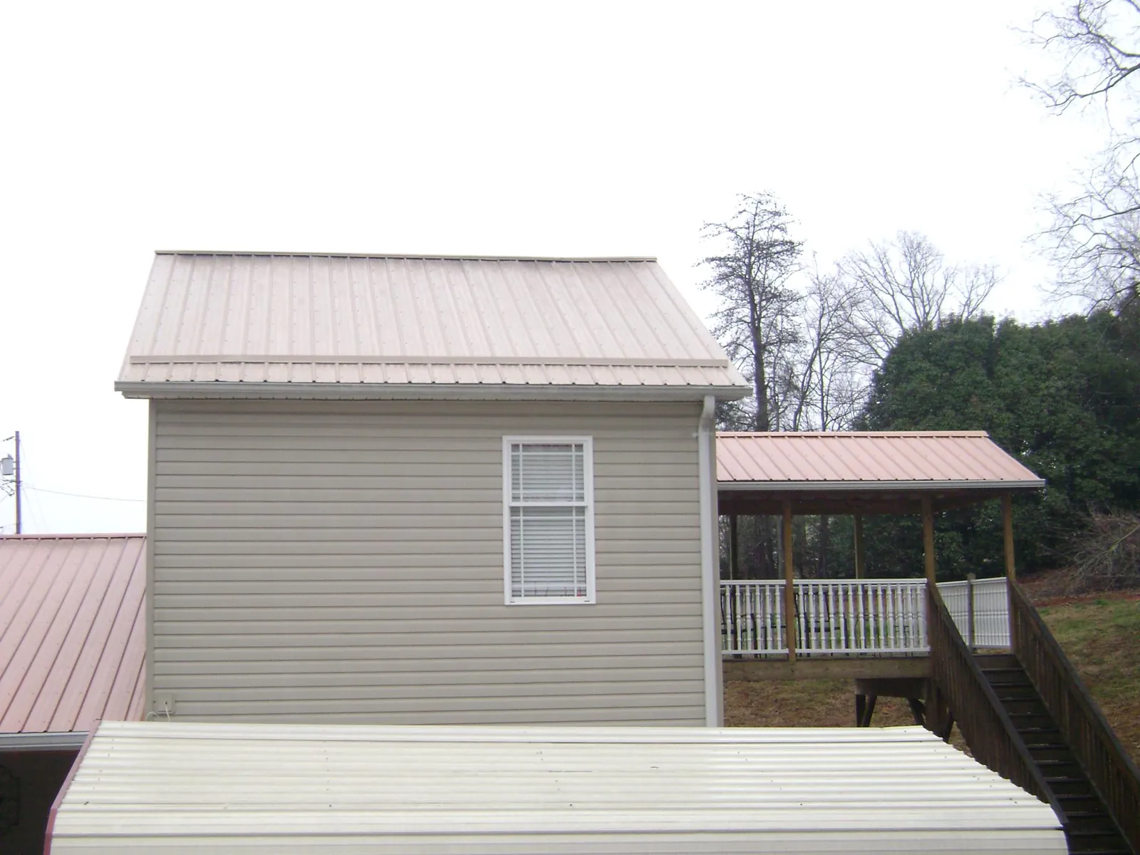 Tan metal roofs on a two story addition and attached porch, from a Roof Replacement job in Etta