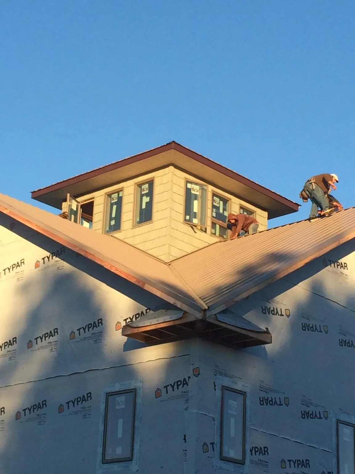Roofers working around a rooftop cupola on a new metal roof at sunset — Roof Waterproofing in Etta by Roofing Brothers